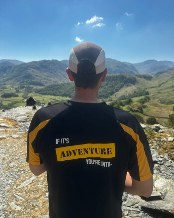 Man looking towards the mountains in a t-shirt saying 