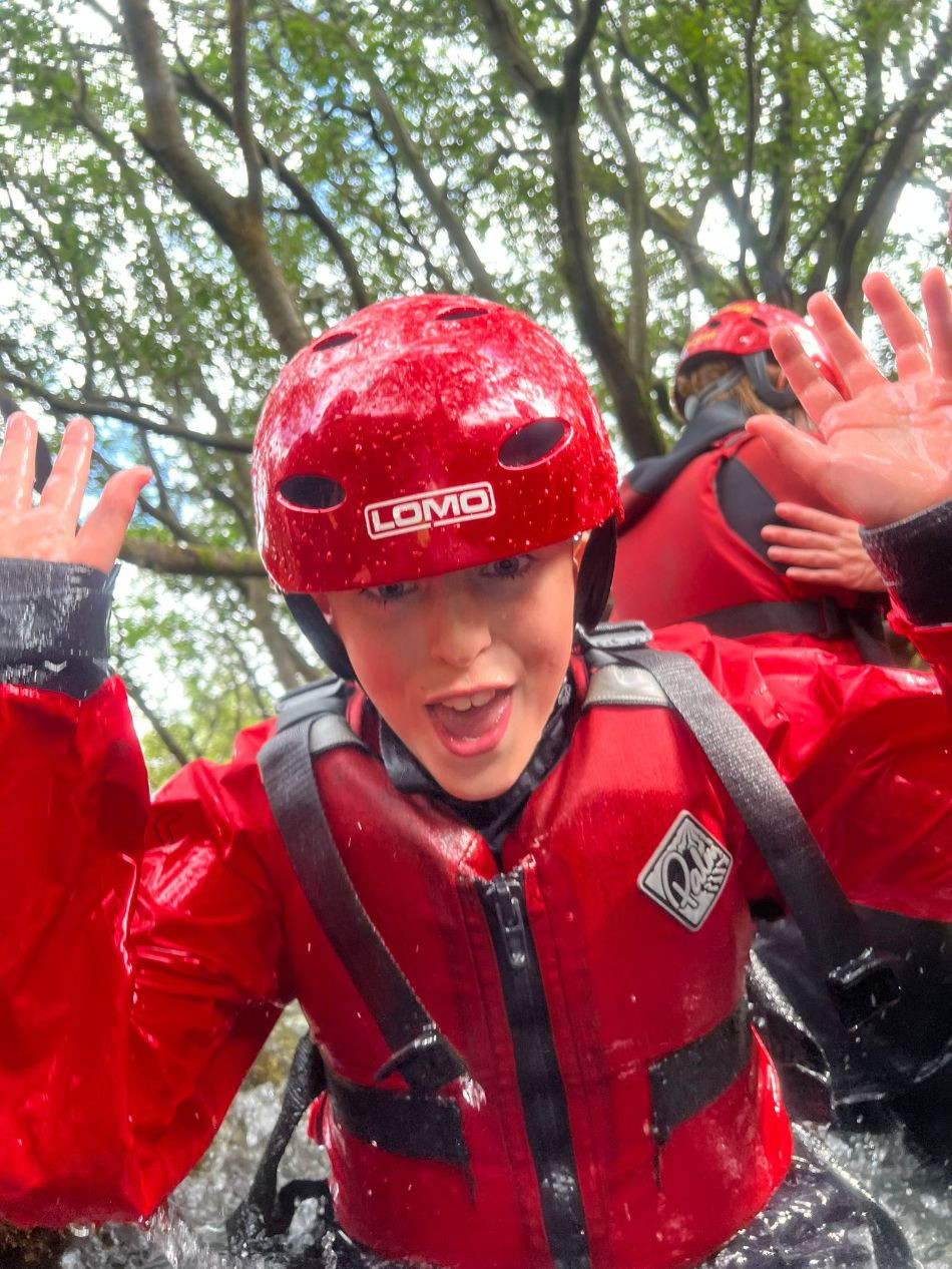 Boy in ghyll scrambling gear pulling a face
