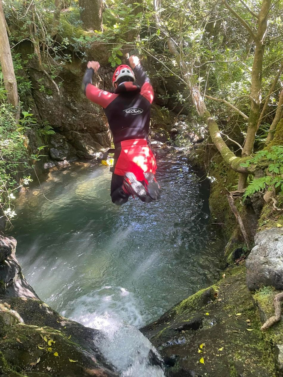 Person jumping off a waterfall into a pool of water