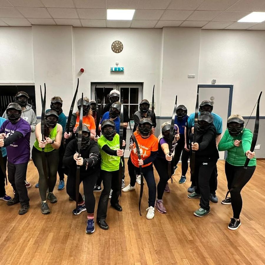 Group of people holding and aiming bows at the camera without arrows