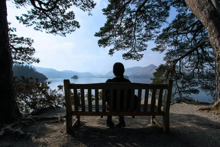 A person looks out at Derwentwater from a bench at Friar's Crag, Keswick