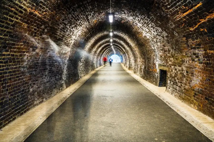 People walking through an old railway tunnel on the Keswick to Threlkeld Footpath