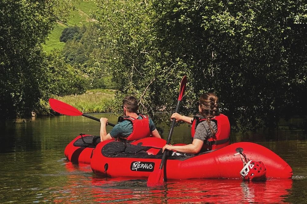 Woman packrafting alongside some geese on the River Derwent
